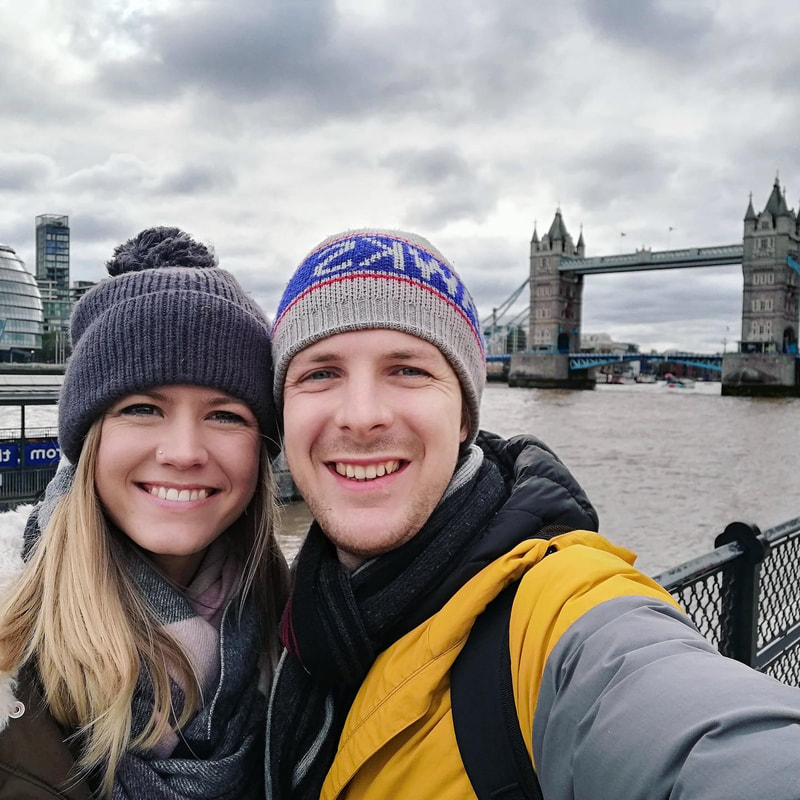 Picture of illustrator (blonde (f)) and husband (brunette (m)) in front of the tower of London